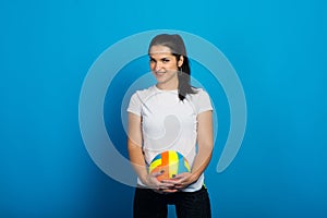 Young beautiful volleyball player isolated on blue in studio