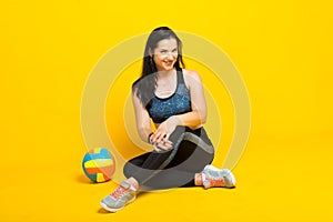 Young beautiful volleyball player isolated on yellow in studio