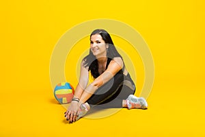 Young beautiful volleyball player isolated on yellow in studio