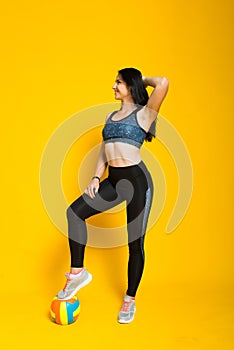 Young beautiful volleyball player isolated on yellow in studio