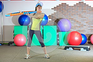 Young beautiful white girl in a yellow and gray sports suit does physical exercises with a hoop at the fitness center.