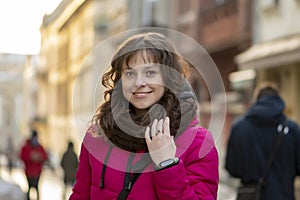 A young beautiful white woman 30-35 years old with curly dark hair smiles against the backdrop of a city landscape