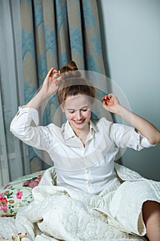 Young beautiful white woman awaking in light room.