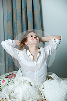Young beautiful white woman awaking in light room.
