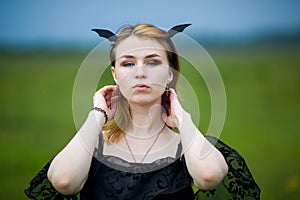 Young beautiful witch in black dress on a summer day. Witchcraft