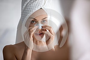 Young beautiful woman applying cleaning strip, removing dark spots.