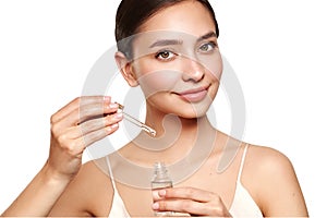 Young beautiful woman applying face serum