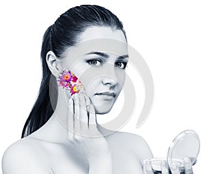 Young beautiful woman applying flowers cosmetic on face.