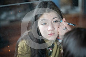 young beautiful woman applying makeup near a mirror in an old apartment