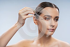 Young beautiful woman applying nature oil under eyes