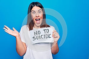 Young beautiful woman asking for psychical problem holding paper with not to suicide message celebrating achievement with happy