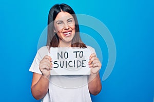 Young beautiful woman asking for psychical problem holding paper with not to suicide message looking positive and happy standing