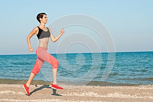 Young beautiful woman athlete running on the beach