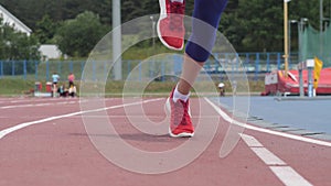 Young beautiful woman athlete starts running at athletics track during a day training in slow motion 4K video on UHD