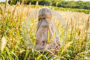 Young beautiful woman in autumn landscape with dry flowers, wheat spikes. Fashion autumn, winter. Sunny autumn, Cozy