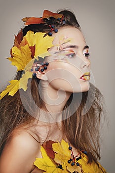 Young beautiful woman with autumn make up and leaves on head. Be