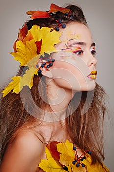 Young beautiful woman with autumn make up and leaves on head. Be