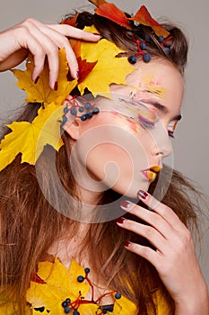 Young beautiful woman with autumn make up and leaves on head. Be