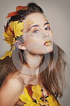 Young beautiful woman with autumn make up and leaves on head. Be