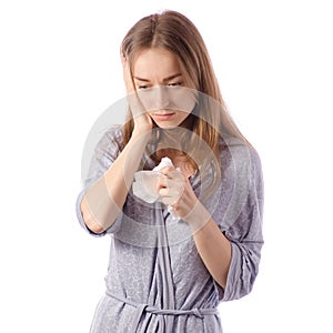 Young beautiful woman in a bathrobe has a headache cold flu napkin