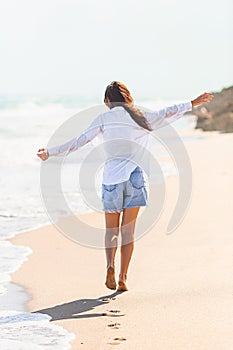 Young beautiful woman on beach vacation walking by the sea