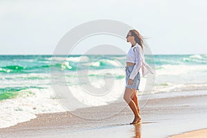 Young beautiful woman on beach vacation walking by the sea