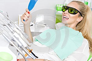 Young beautiful woman with beautiful white teeth sitting on a dental chair.