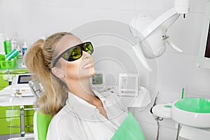 Young beautiful woman with beautiful white teeth sitting on a dental chair.