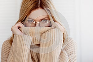 Young beautiful woman in beige sweater and glasses. Attractive blonde.