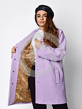 Young beautiful woman in beret demonstrates lining inside of a new medium length fashion casual pink winter jacket coat