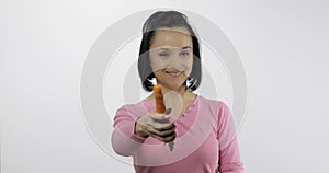 Young beautiful woman with big carrot. Offer bite to viewer.