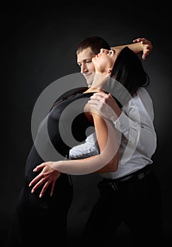 Young beautiful woman in black dress and man in white shirt dancing tango.