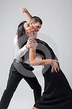 Young beautiful woman in black dress and man in white shirt dancing tango.