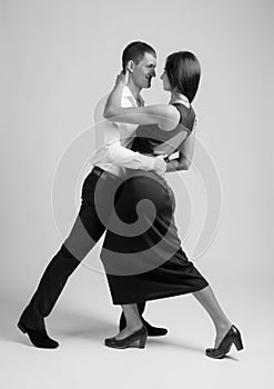 Young beautiful woman in black dress and man in white shirt dancing tango.