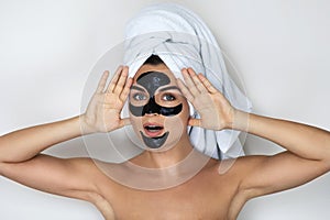 Young and beautiful woman with black peel-off mask on her face