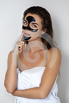 Young and beautiful woman with black peel-off mask on her face