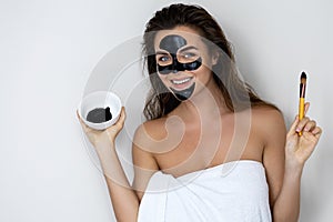 Young and beautiful woman with black peel-off mask on her face