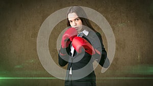 Young beautiful woman in black suit and white shirt standing in combat pose with red boxing gloves. Business concept.