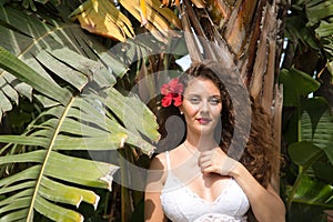 Young and beautiful woman, blonde, with curly hair and blue eyes, with a white top, next to some palm trees, with a red Pacific