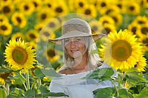 Young beautiful woman on blooming sunflower field in summer