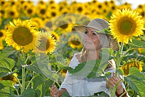 Young beautiful woman on blooming sunflower field in summer