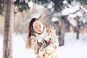 Young beautiful woman blowing snow in winter