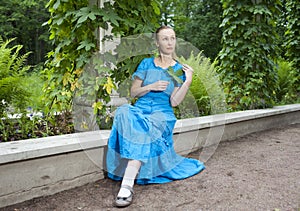 Young beautiful woman in a blue dress in the arbor twined a green bindweed