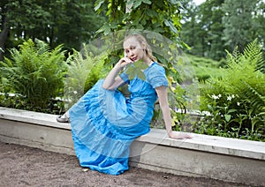 Young beautiful woman in a blue dress in the arbor twined a green bindweed