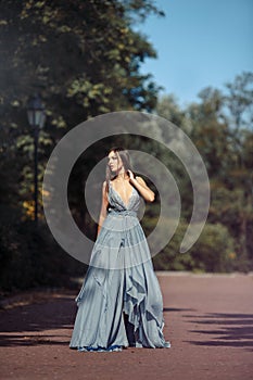 Young beautiful woman blue dress walking path in park.