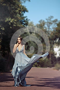 Young beautiful woman blue dress walking path in park.