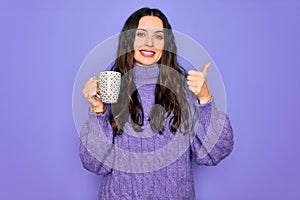 Young beautiful woman with blue eyes drinking mug of coffee over isolated purple background happy with big smile doing ok sign,