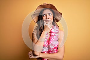 Young beautiful woman with blue eyes on vacation wearing bikini and hawaiian lei with hand on chin thinking about question,