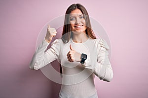 Young beautiful woman with blue eyes wearing casual white t-shirt over pink background Pointing to the back behind with hand and