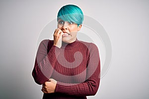 Young beautiful woman with blue fashion hair wearing casual sweater over white background looking stressed and nervous with hands